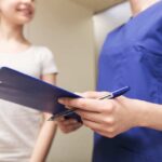 Close-up of nurse with clipboard and young girl
