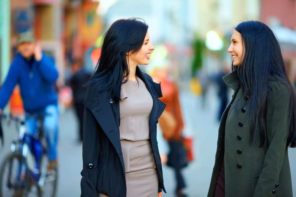 Two young women talking and smiling in outdoor space