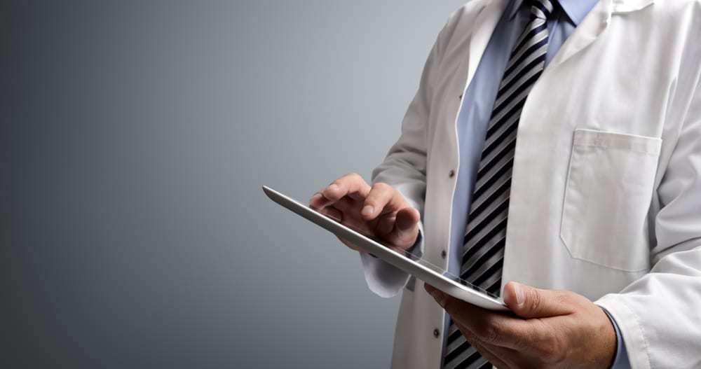 Close-up male doctor using tablet