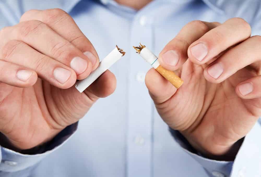 Close-up of man ripping cigarette in half