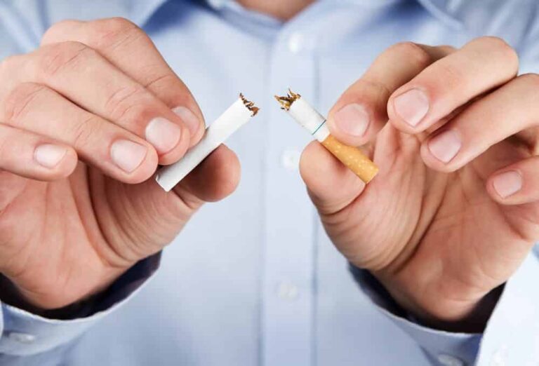 Close-up of man ripping cigarette in half