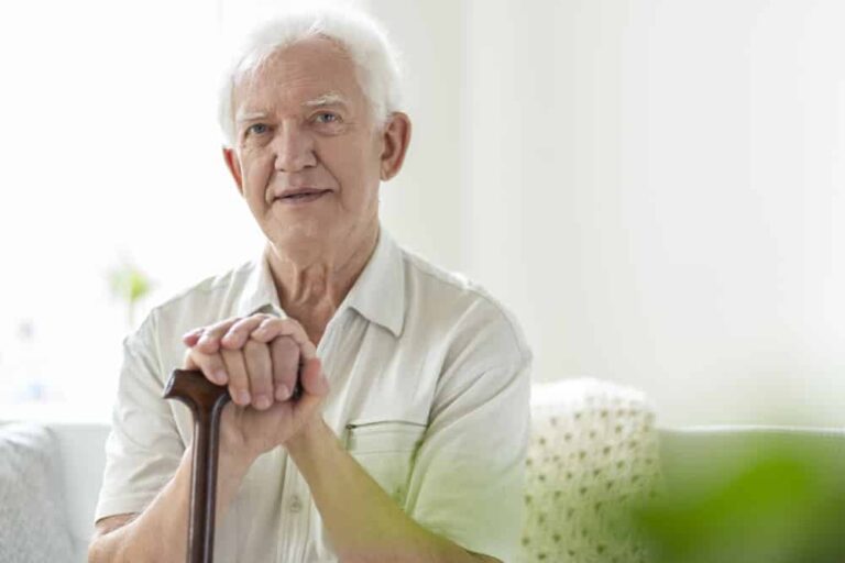 Senior man sitting, holding a walking stick