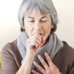 Senior woman coughing into hand