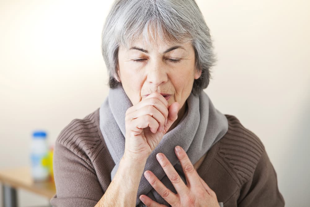 Senior woman coughing into hand