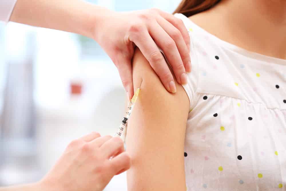 Medical professional administering vaccine in woman's arm