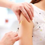 Medical professional administering vaccine in woman's arm