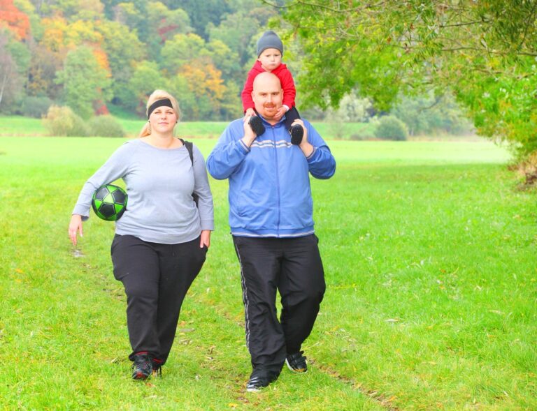 Overweight couple in athletic gear walking outside, toddler son on dad's shoulders