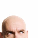 Cropped image of bald man looking up on white background