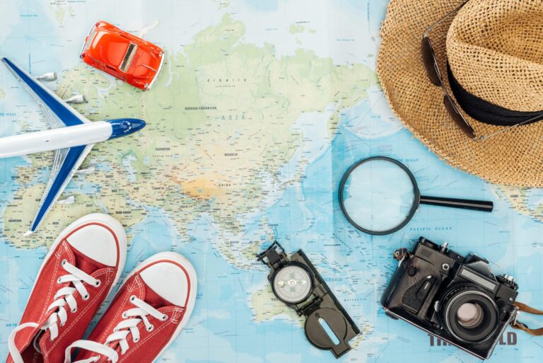 World map beneath camera, shoes, sunhat, sunglasses, plane model, etc