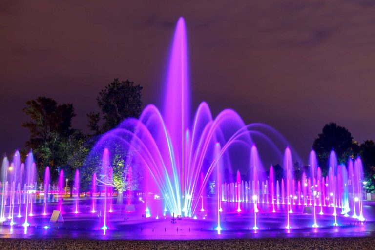 Water fountain lit up purple and pink at night