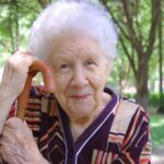 Portrait-of-smiling-senior-woman-outside-with-cane