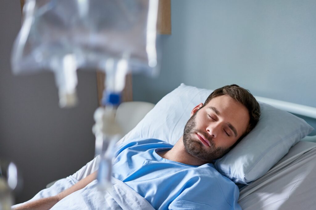 Young-man-lying-in-hospital-bed-with-eyes-closed