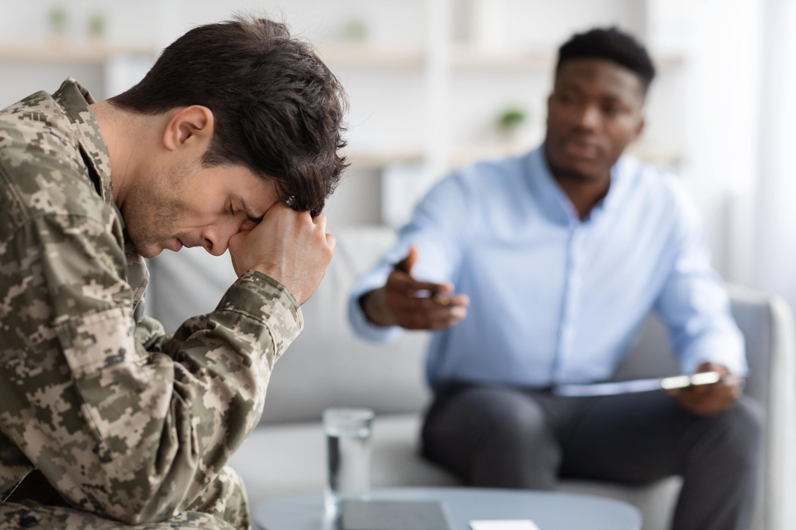 Young male soldier appearing distressed as he talks to therapist