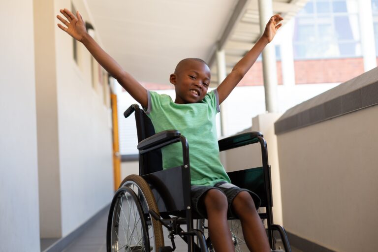 Happy young boy in wheelchair with his arms up