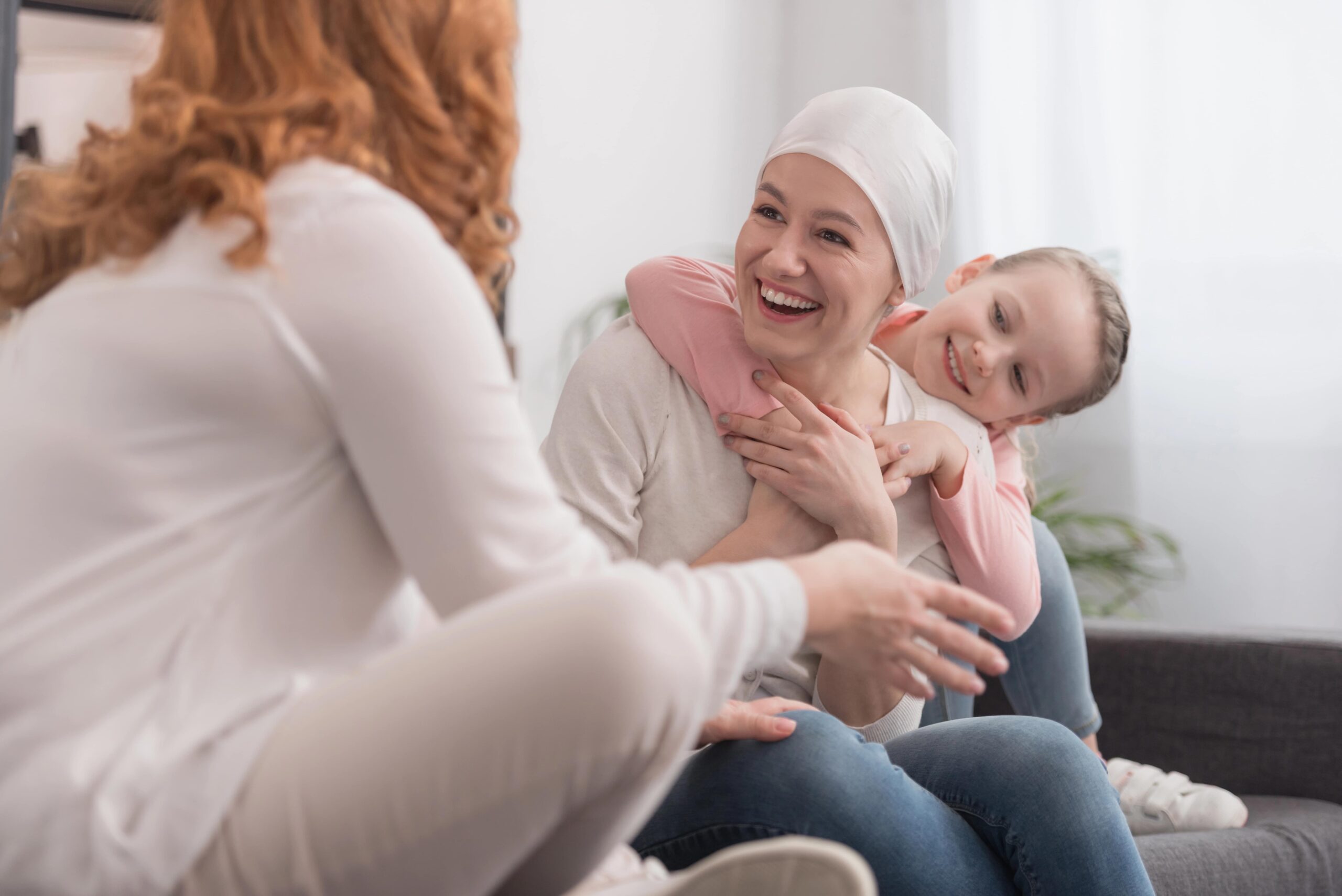 Happy family smiling together, woman wearing scarf on head due to chemo treatment