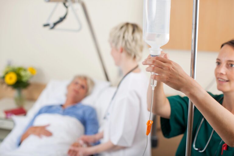 nurse adjusting infusion bottle with patient and doctor in background