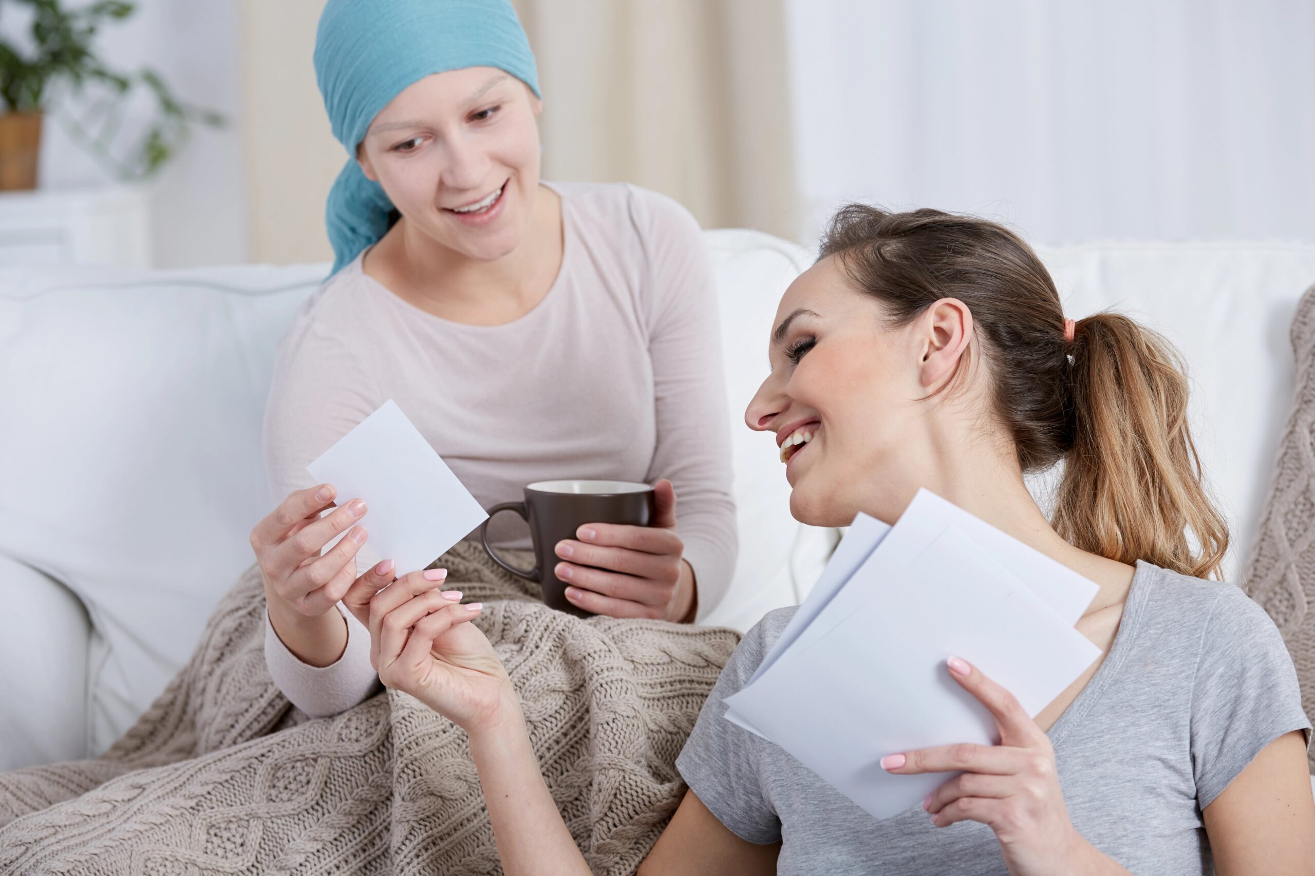 Young woman with cancer, smiling and sharing photos with sister