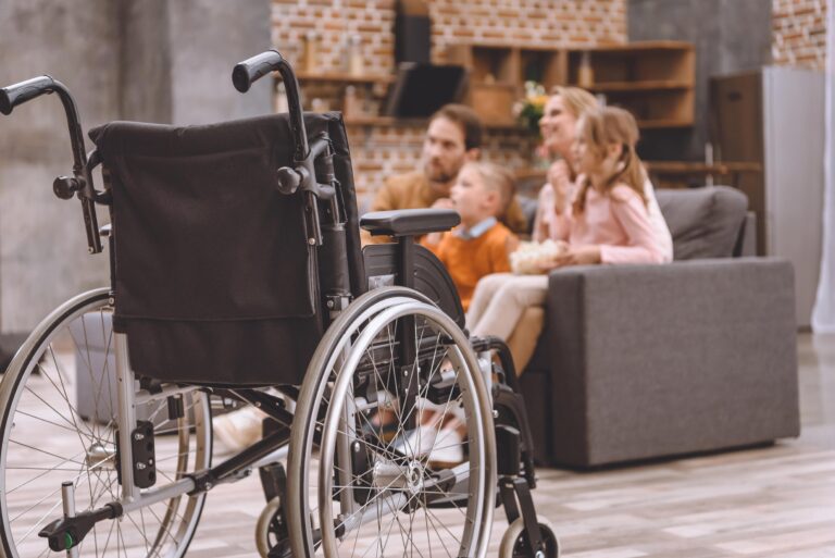 Child-size wheelchair, happy family in background