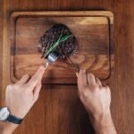 Close-up of hands using knife to cut steak