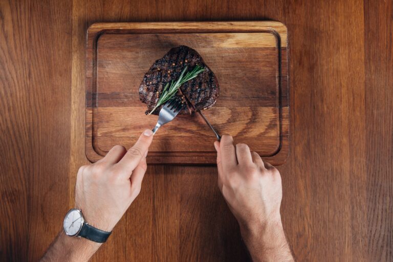 Close-up of hands using knife to cut steak