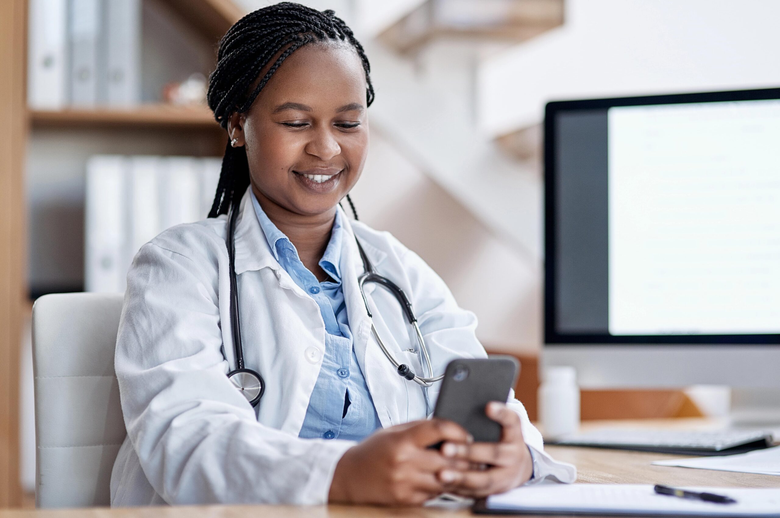 Young smiling doctor looking at phone at hospital