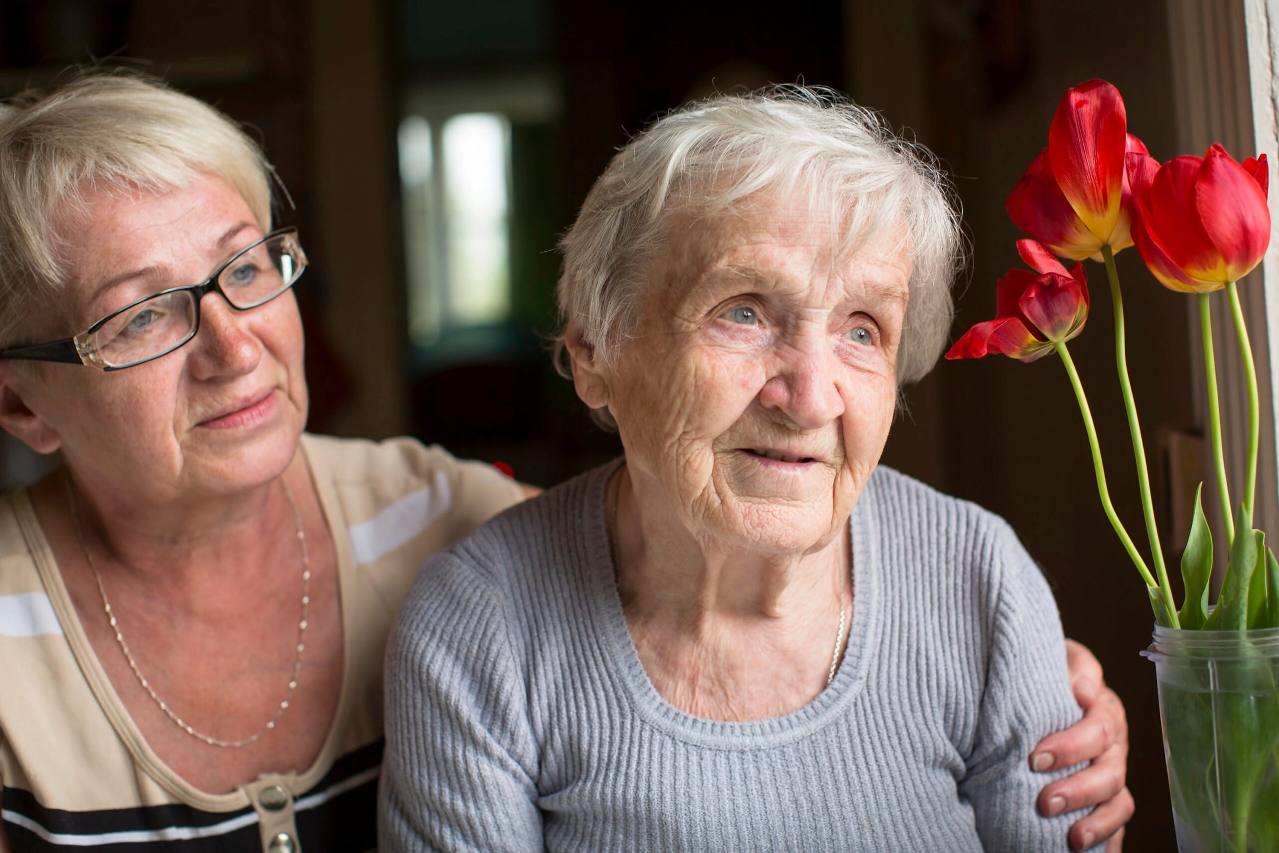 Woman hugging older woman near window