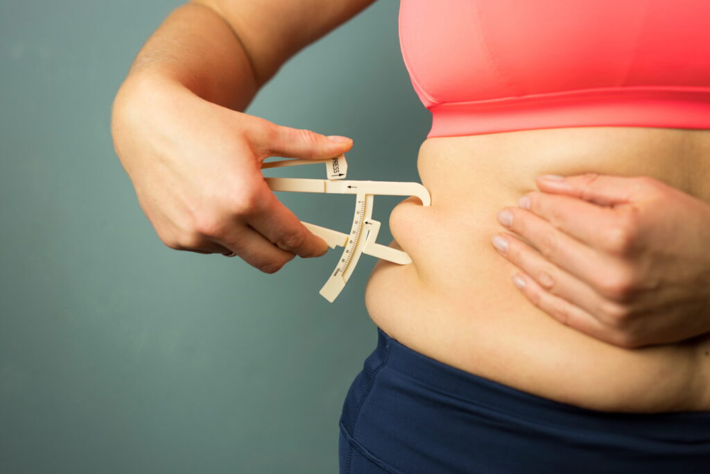 woman using fat caliper on belly