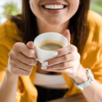 Smiling young woman holding cup of coffee