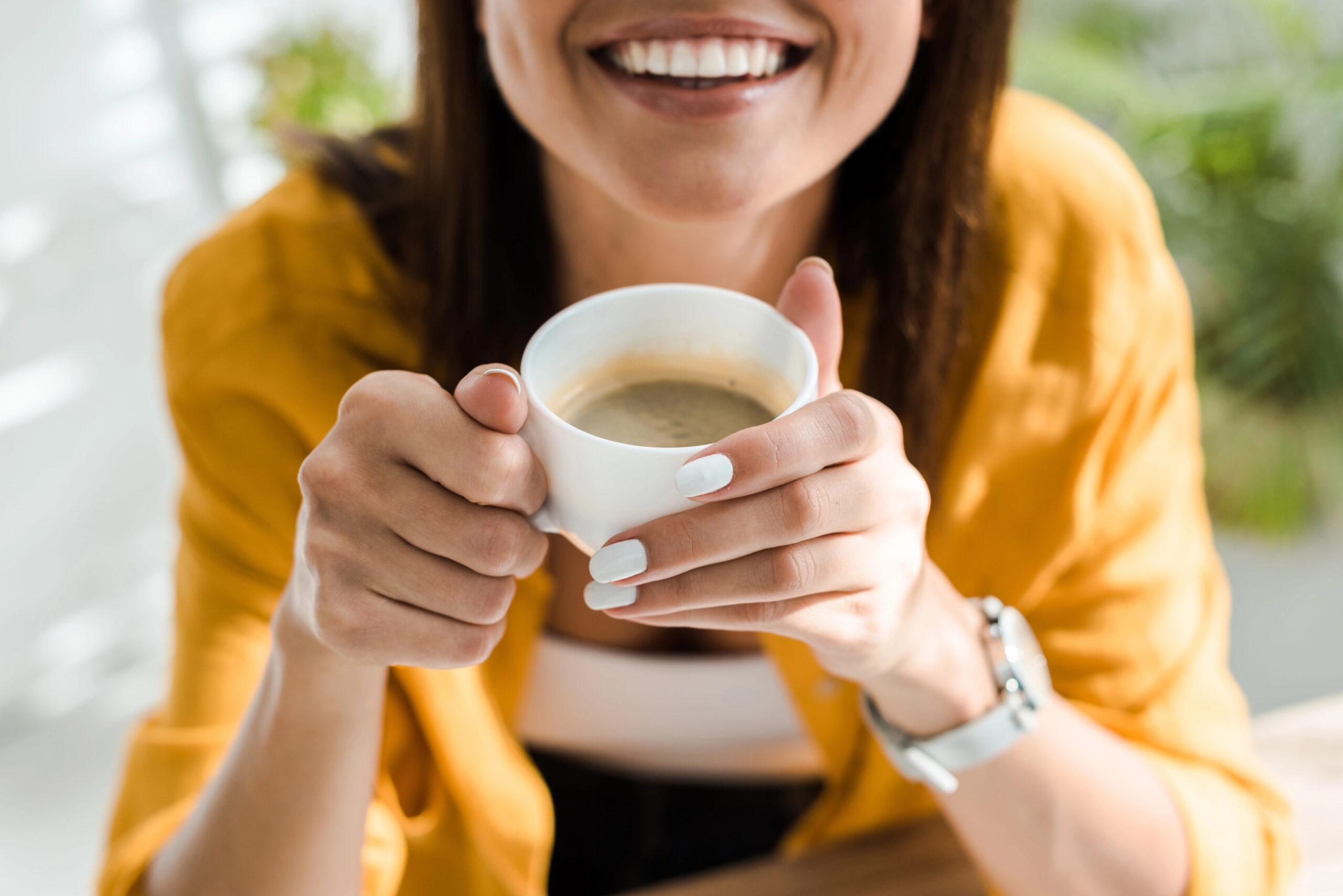 Smiling young woman holding cup of coffee