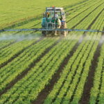 Tractor spraying pesticides over field