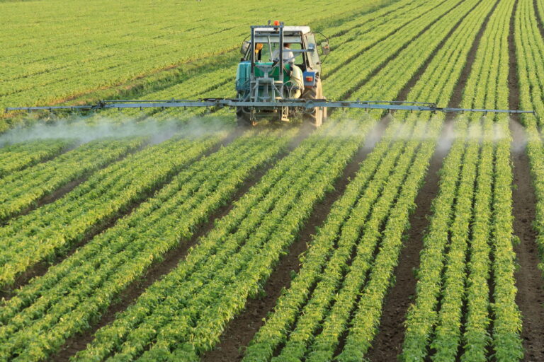 Tractor spraying pesticides over field