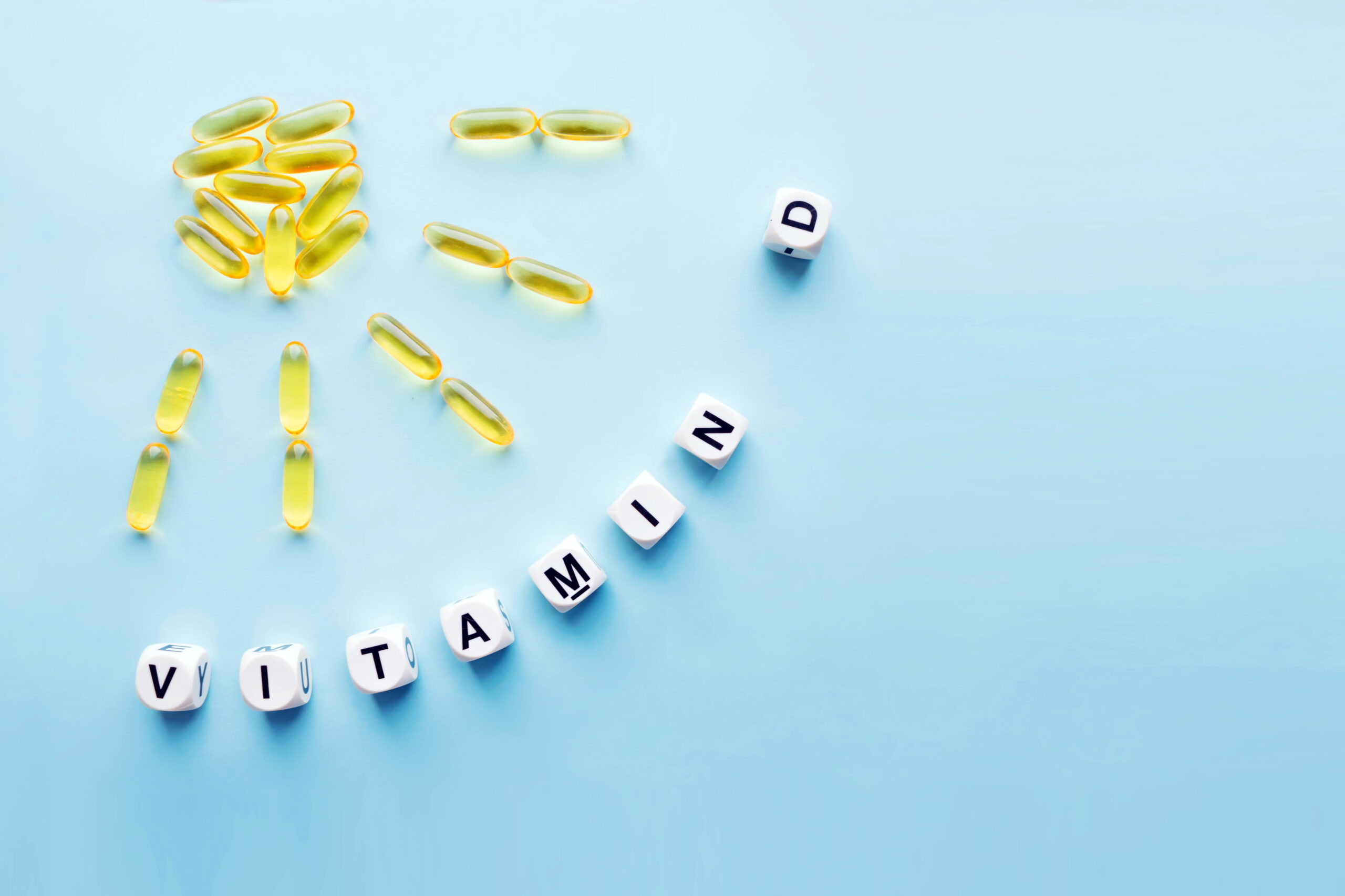 vitamin D pills arranged in shape of sun, blocks spelling vitamin D