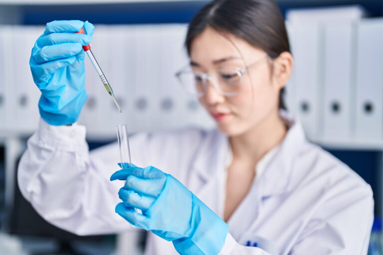 Young female scientist adding liquid to test tube in laboratory