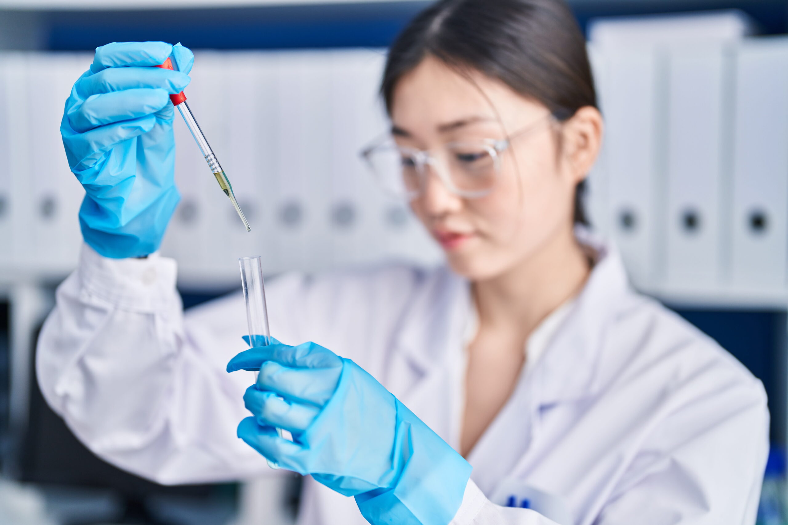 Young female scientist adding liquid to test tube in laboratory