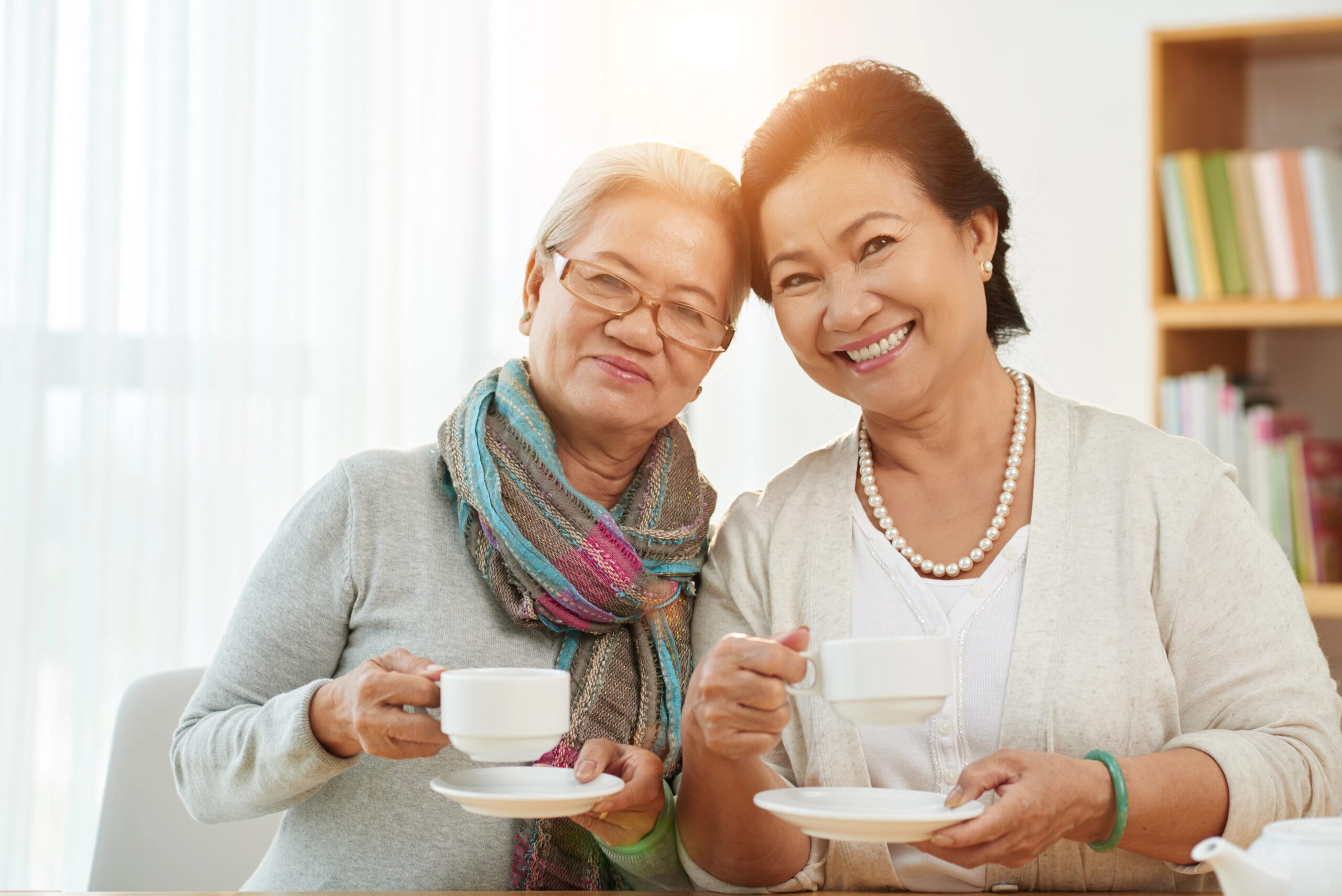 Two smiling older women drinking coffee