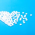 Pills arranged in shape of heart, scattered on one side