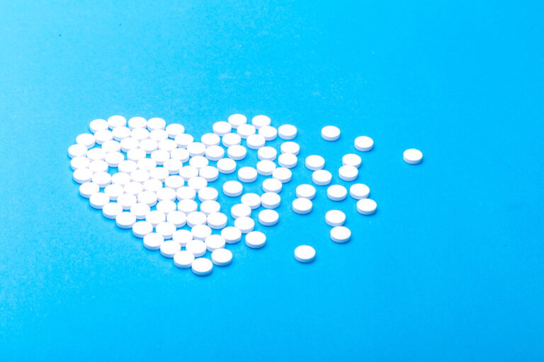 Pills arranged in shape of heart, scattered on one side