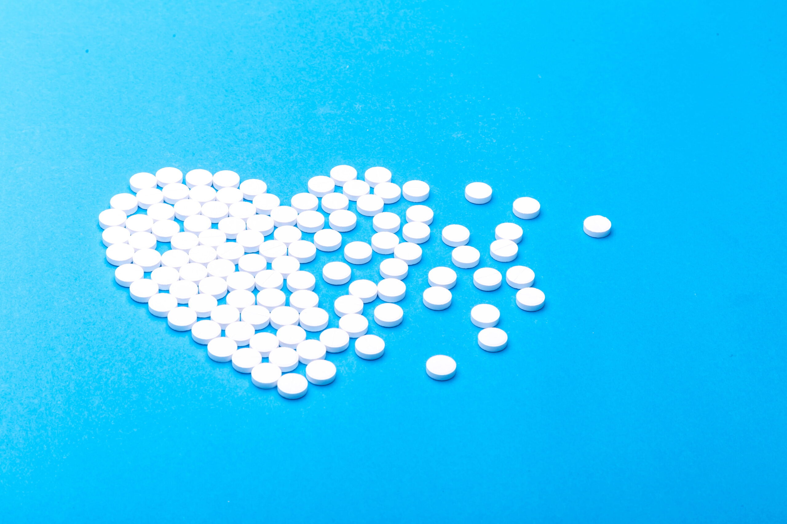 Pills arranged in shape of heart, scattered on one side