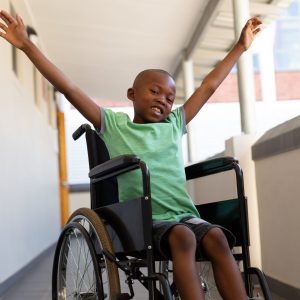 Happy young boy in wheelchair with his arms up