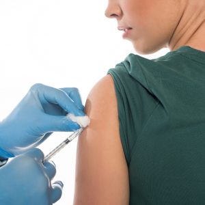 Healthcare professional administering vaccine to young woman