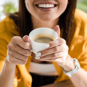 Smiling young woman holding cup of coffee