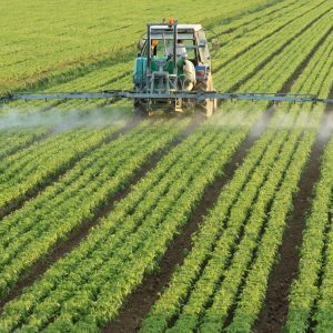 Tractor spraying pesticides over field