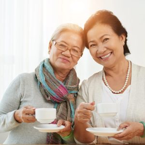 Two smiling older women drinking coffee