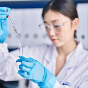 Young female scientist adding liquid to test tube in laboratory