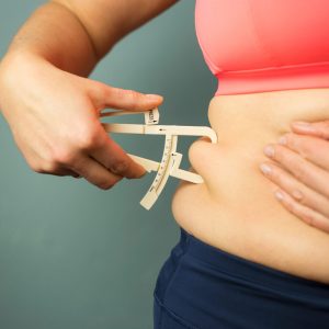 woman using fat caliper on belly